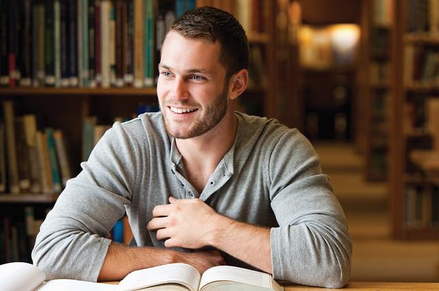 Un homme à la librairie souriant avec des livres sur sa table.