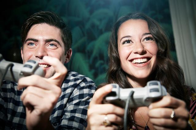 Deux adultes manettes à la main jouant aux jeux vidéo.